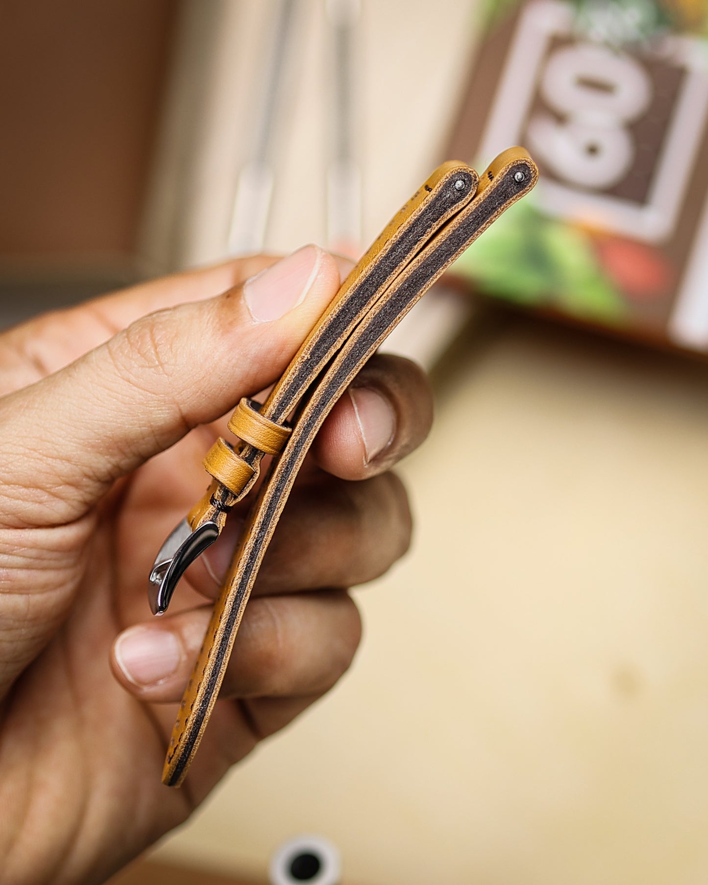 Hand holding a leather watch strap with a blurred background